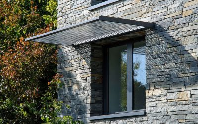 Modern window with metal awning on stone wall. Stylish architectural detail providing shade and protection.