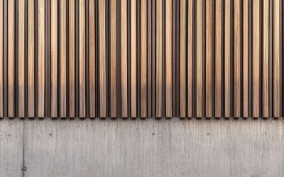 A modern architectural surface features vertical wooden slats above a concrete wall with textural details and patterns.