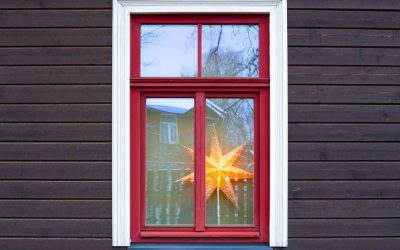 Wall of a wooden private house with a red window frame. Christmas star on the windowsill. Winter.
