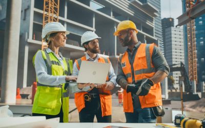 Portrait of a Site Manager Talking with General Operatives at a Residential Building Construction Area. Female and Male Employees Using a Laptop Computer to Oversee the Real Estate Project Plan