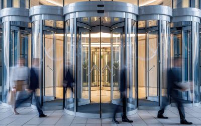 A dynamic scene of professionals hurrying through a modern revolving door, showcasing a blend of movement and architectural elegance in a corporate setting.