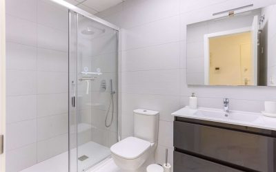 Minimalist bathroom design featuring walk-in shower, toilet, and sleek black vanity unit