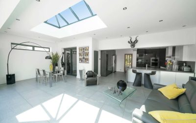Interior of modern, bright, white and grey designer open plan kitchen diner and lounge, with skylight roof lantern.