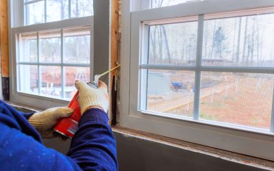 Contractor is sealing gaps around window frame with insulation foam during home renovation project